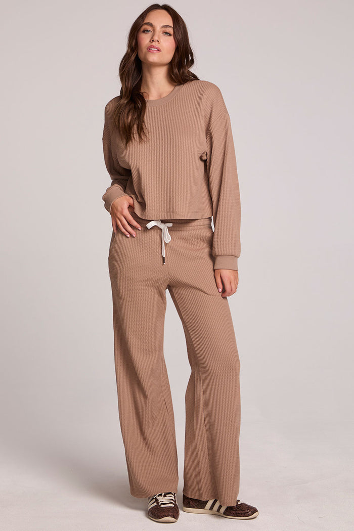 Full body front view of a woman wearing the Chaser Jorgia Camel Pants on a neutral background with matching top