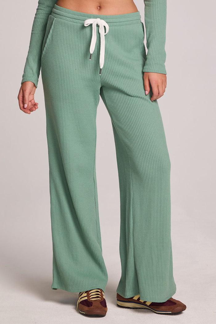 Front view of a woman wearing the Chaser  Jorgia Verdelle Pants on a neutral background with green shirt