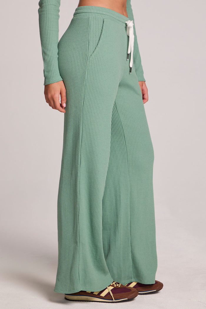 Side view of a woman wearing the Chaser  Jorgia Verdelle Pants on a neutral background with shirt