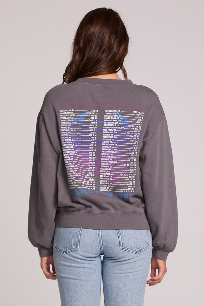 Back view of a woman wearing the Chaser Journey 1983 Tour Sweatshirt on a neutral background with jeans