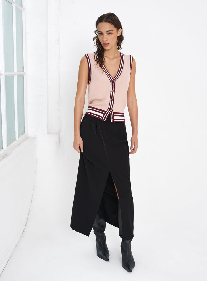 Woman wearing a sleeveless knitted button through vest top with a black midi skirt
