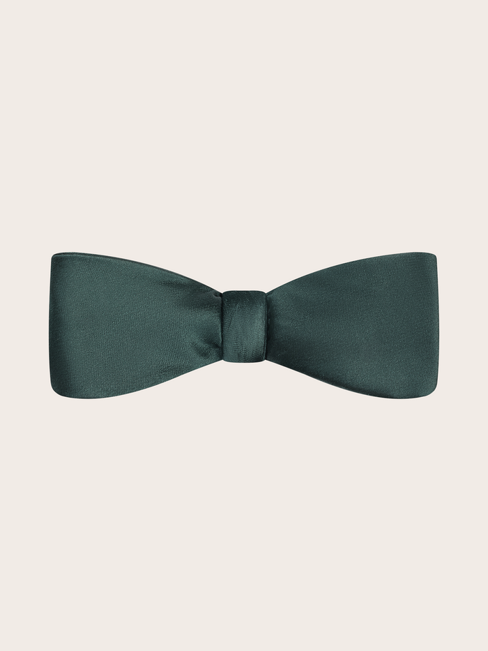 A pre-tied juniper green satin bow tie against a light neutral background