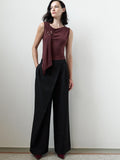 A woman wearing black high waisted Trousers with an a asymmetric waistband front overlay, front pleats, 2 side pockets, a wide leg Full length tailored full length silhouette.