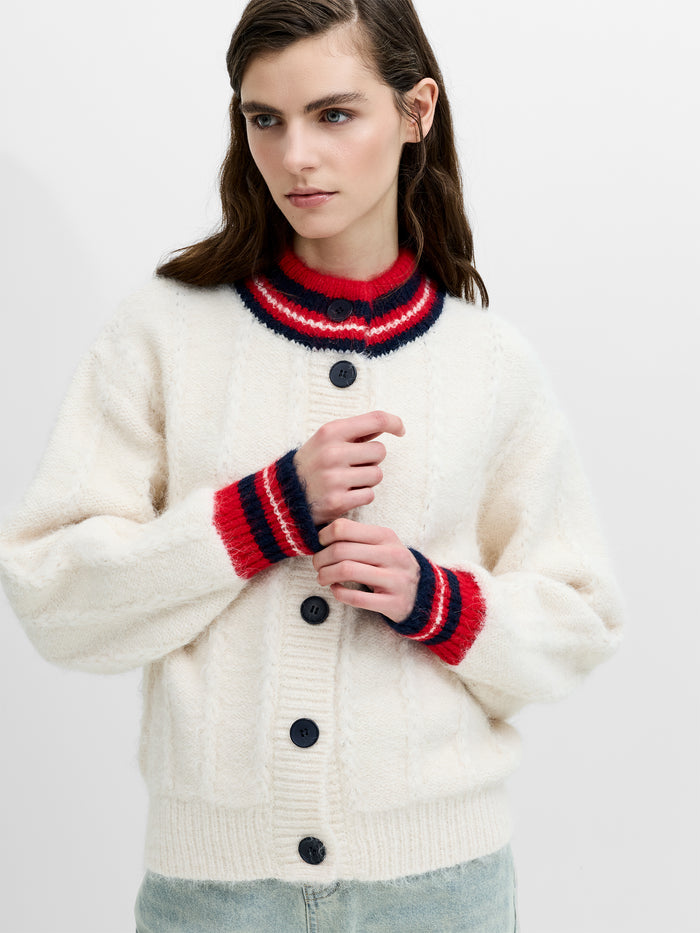A woman wearing a relaxed fit cream cardigan with multi-coloured contrast trim, a button down fastening and a high neckline.