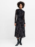 A woman wearing a long sleeved mesh midi dress featuring a black and brown floral print, a boat neckline, and gathered side detailing.