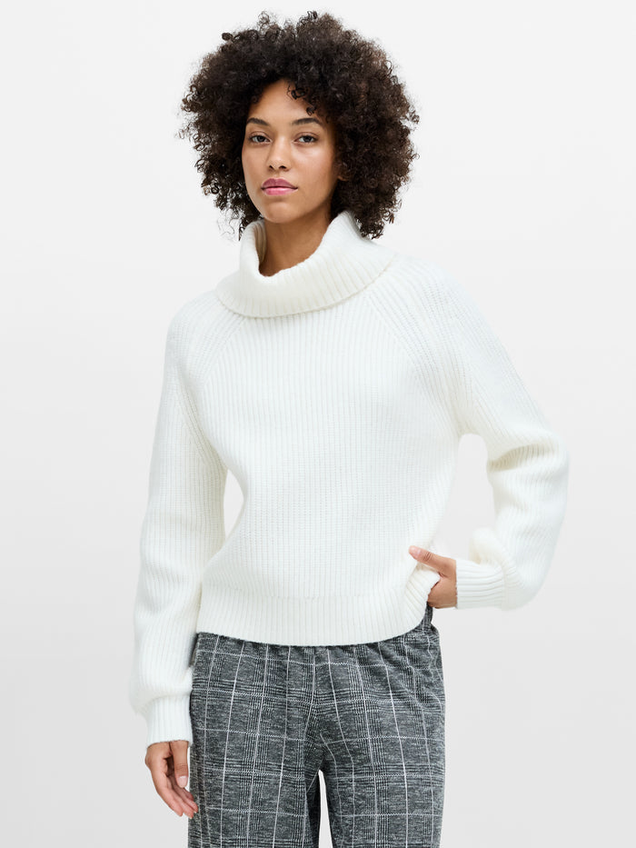 A woman wearing a cream funnel neck knit jumper with long sleeves, a regular fit and a ribbed hem.