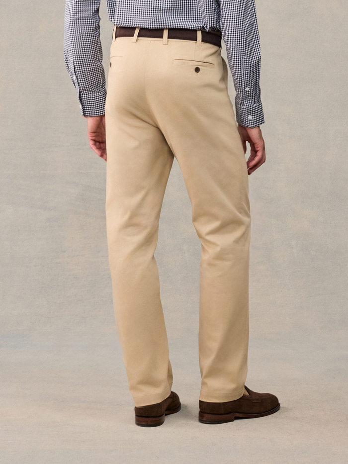 Cropped back view of khaki chino trousers with brown leather belt and suede loafers