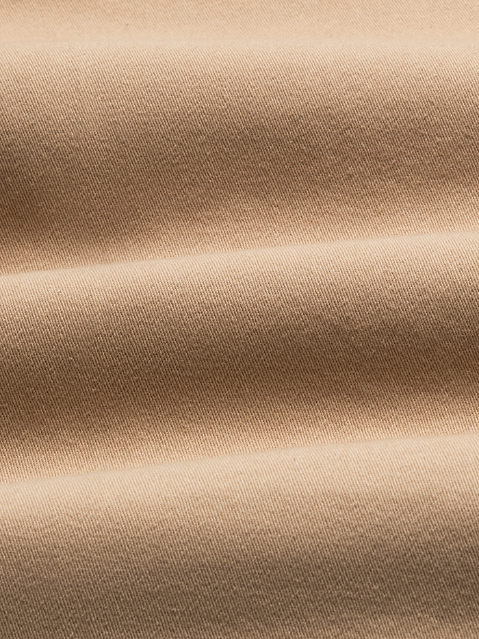 Close-up of khaki chino fabric with folds, showing woven texture