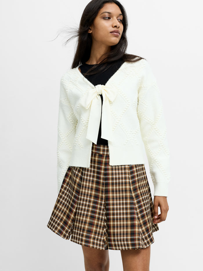 A woman wearing a cream bobble knit cardigan with a bow fastening, long sleeves and a regular fit.