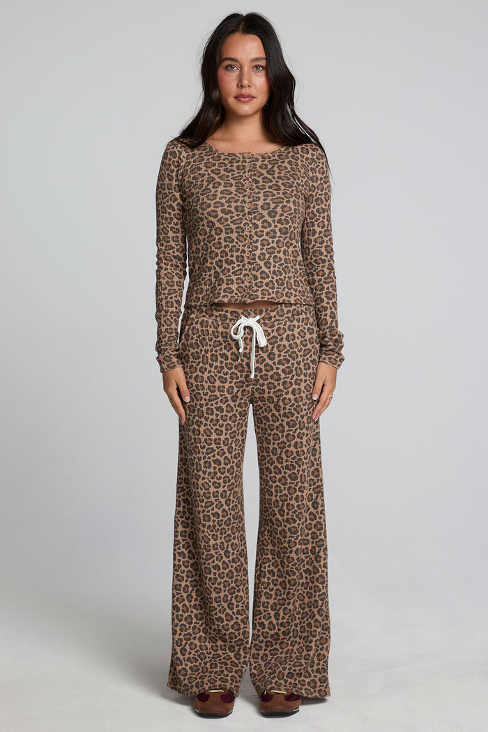 Full body front view of a woman wearing the Chaser Klara Leopard Button Down Top on a neutral background with matching leopard print lounge pants