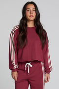 Front view of a woman wearing the Chaser Kloud Burnt Red Sweatshirt on a neutral background with matching red pants