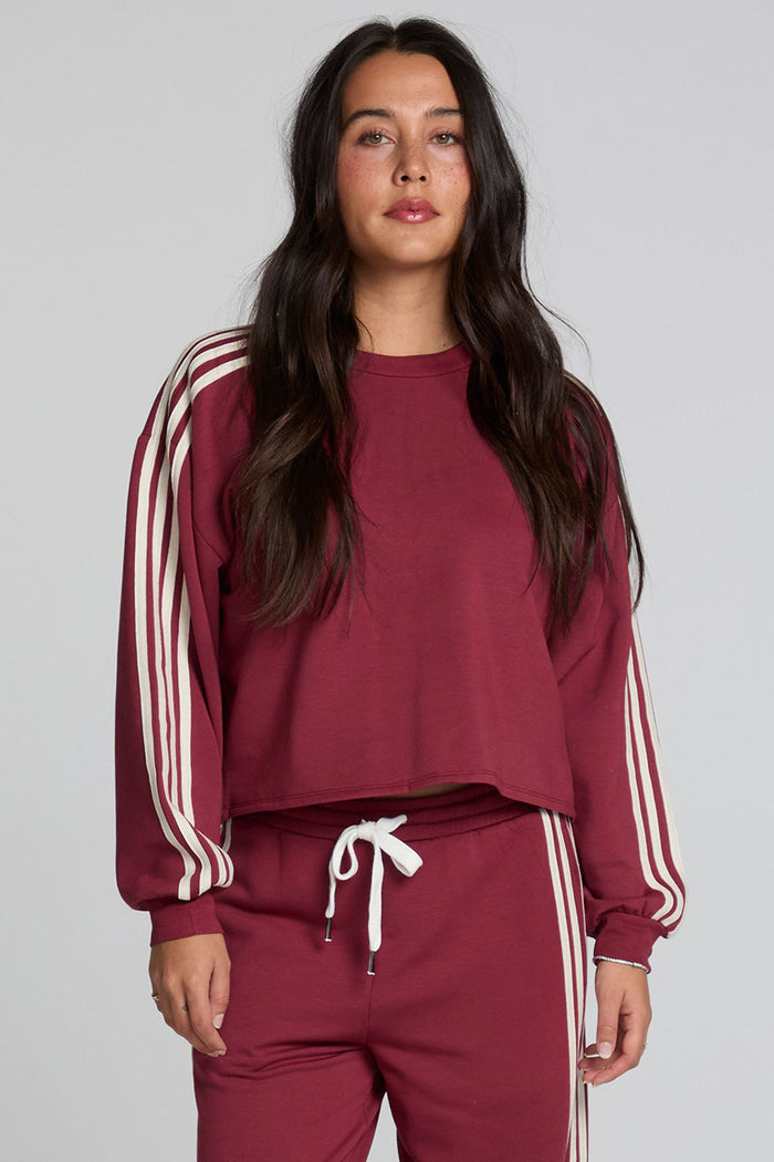 Front view of a woman wearing the Chaser Kloud Burnt Red Sweatshirt on a neutral background with matching red pants