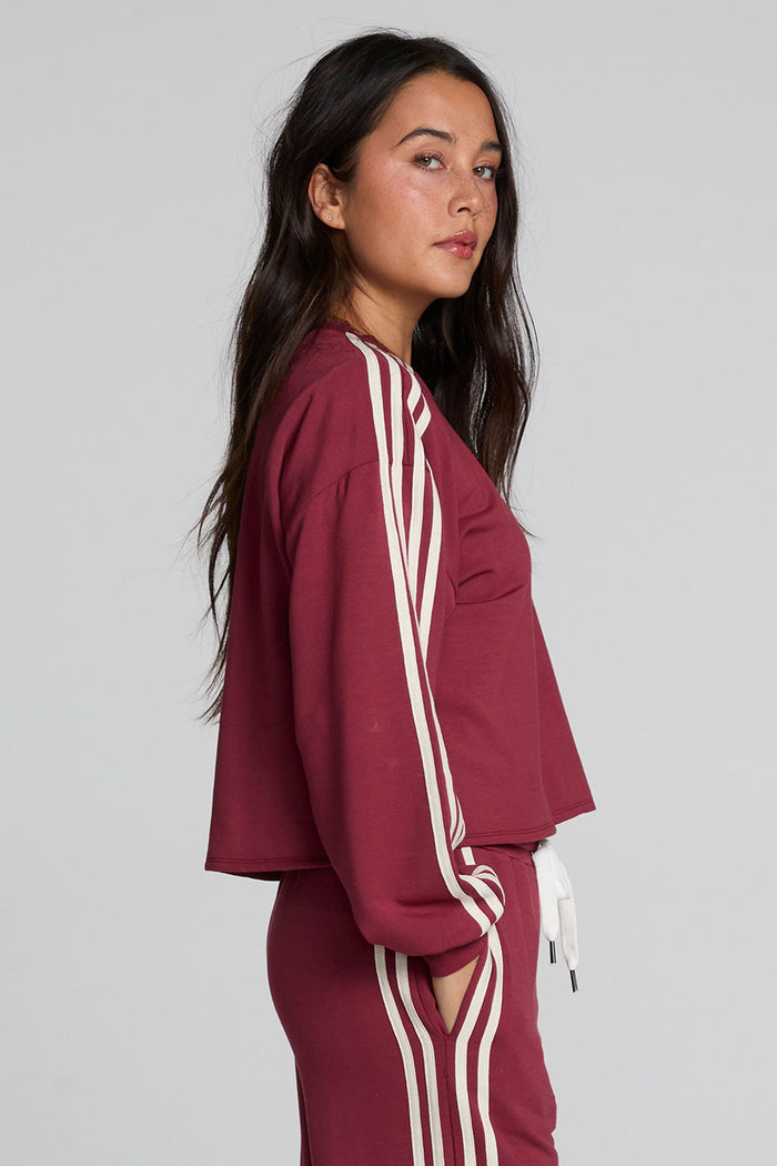 Side view of a woman wearing the Chaser Kloud Burnt Red Sweatshirt on a neutral background with matching pants