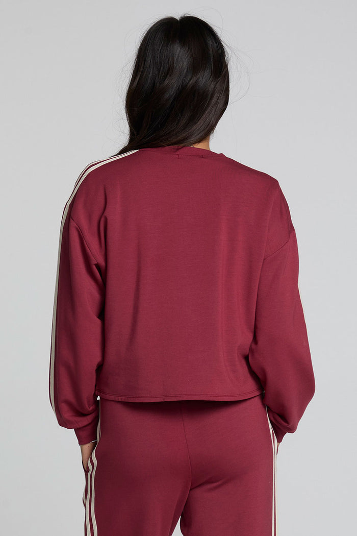 Back view of a woman wearing the Chaser Kloud Burnt Red Sweatshirt on a neutral background with pants