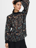 A woman wearing a relaxed fit semi-sheer black blouse with long sleeves, a multi-colored abstract print and high neckline.