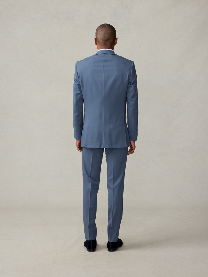 Back view of man in lake blue shawl-lapel tuxedo, full-length