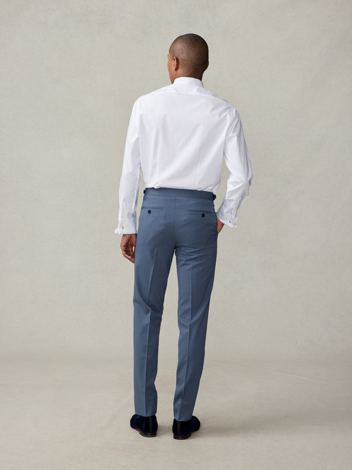 Back view of man in lake blue tuxedo trousers, navy velvet loafers, full-length