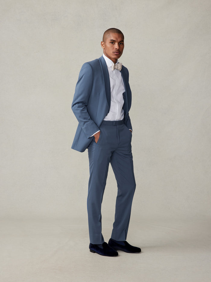 Man in lake blue shawl-lapel tuxedo, ivory bow tie, and white shirt, full-length front view