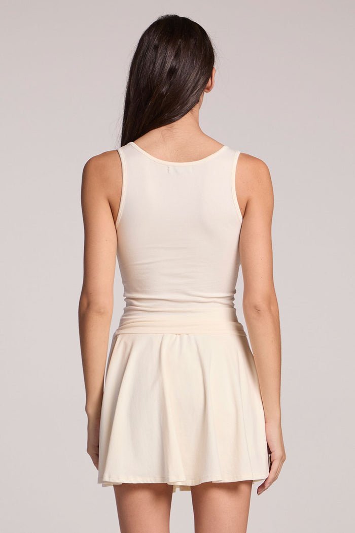 Back view of a woman wearing the Chaser Lander Coconut Milk Tank on a neutral background with hands at her sides