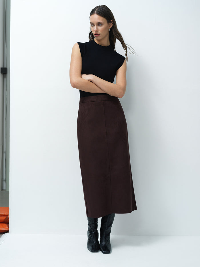 A woman wearing a brown faux suede midi skirt with a back zip fastening and a high waist.