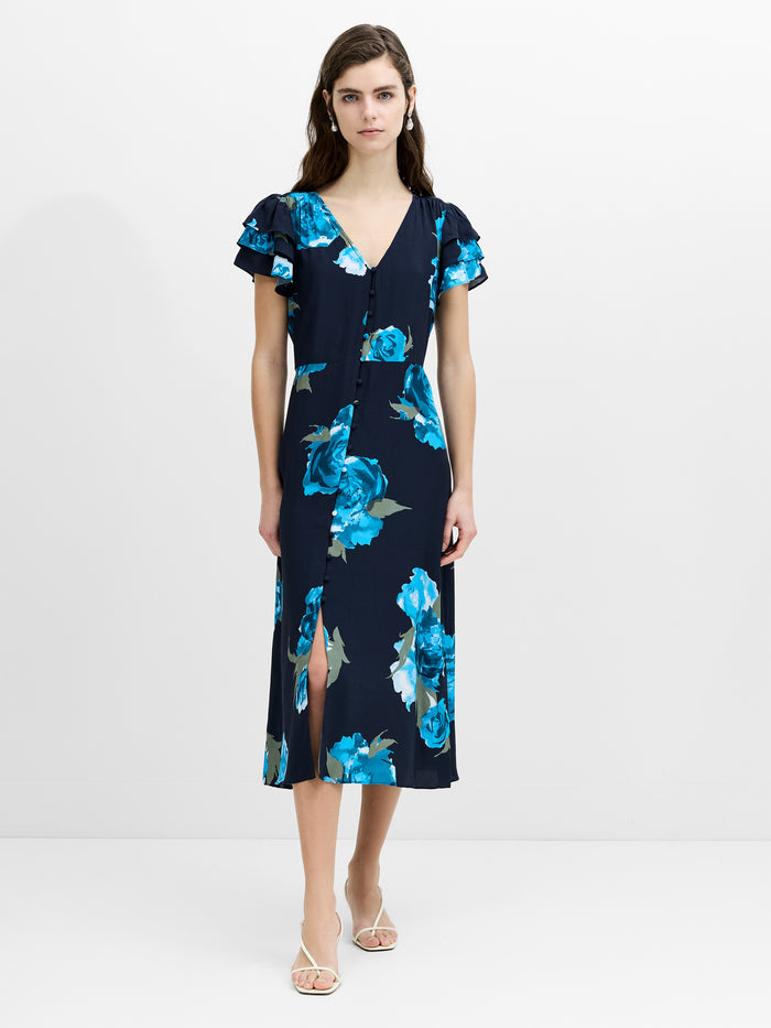 A woman wearing a floral button down flowing midi length blue dress with layered frill sleeves and front split hem.