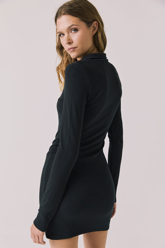 Back view of woman wearing Chaser’s Lara True Black Mini Dress with long sleeves on a white background