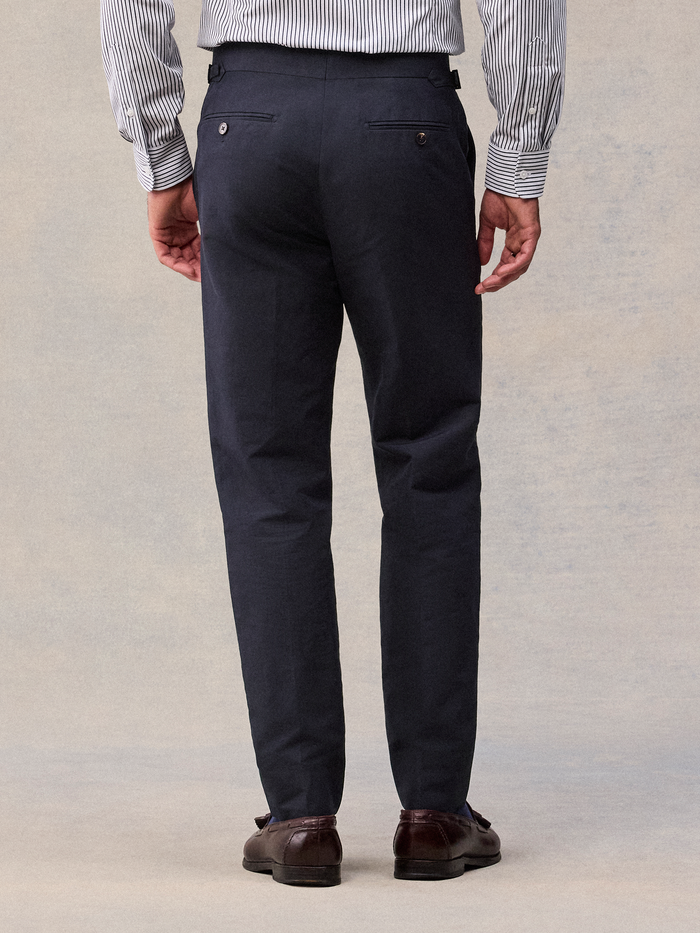 Deepwater navy linen trousers from behind, buttoned welt back pockets, cropped view.