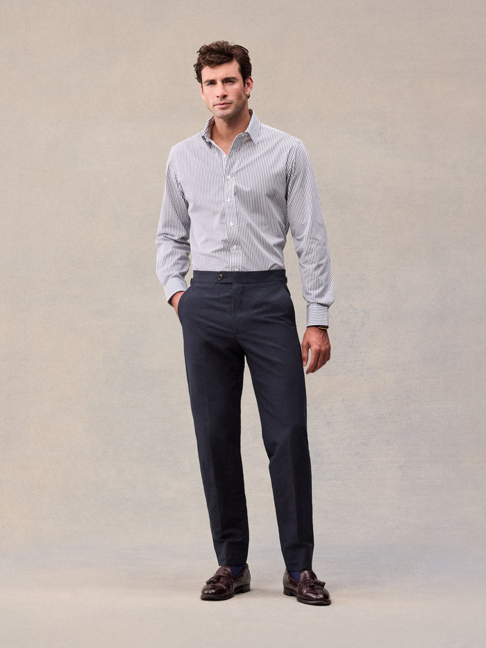 A man in deepwater navy linen trousers and a striped shirt, full length front view.