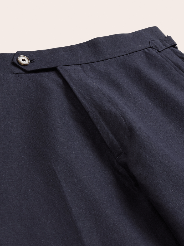 Close-up of deepwater navy linen trousers waistband, horn button and side-adjuster tab.