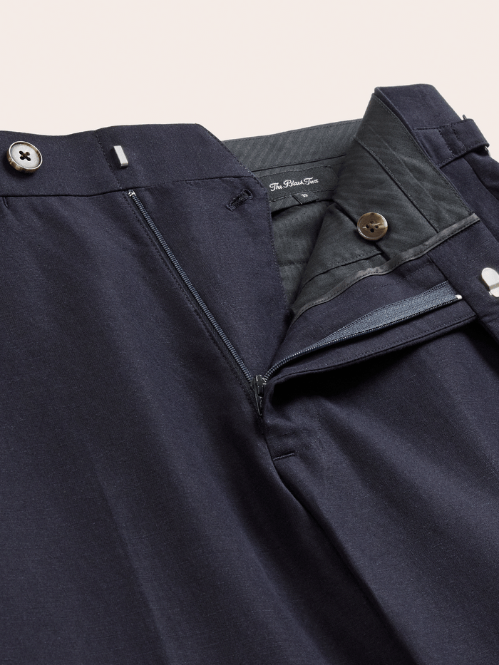 Deepwater navy linen trousers with the fly open, showing zip closure and interior label.