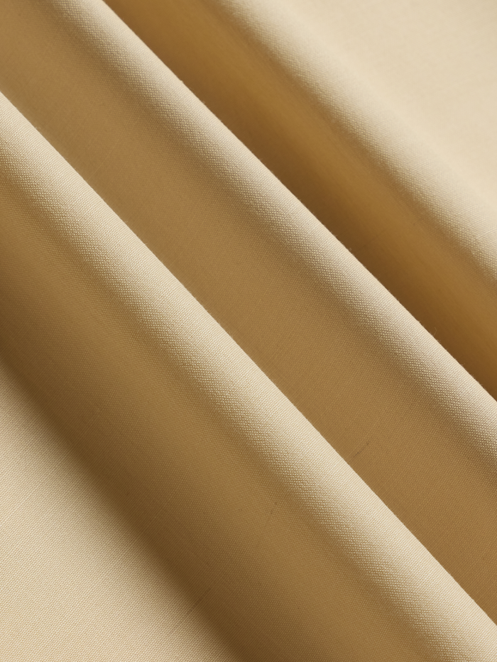 Harvest tan linen suit fabric folded to show its plain weave and soft matte finish