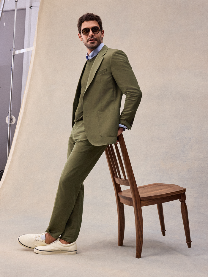 Editorial shot of vintage olive suit styled with a knit and cream canvas sneakers