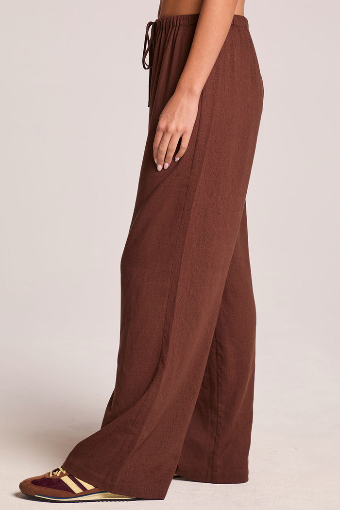 A full body front view of a woman wearing the Chaser  Lee Kahlua Trouser on a neutral background with one foot forward
