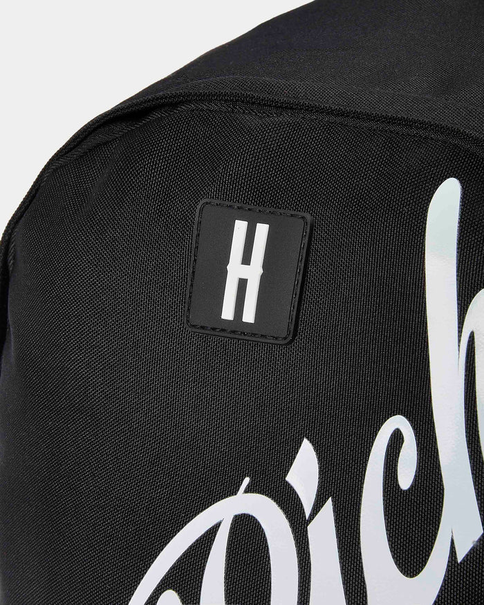 Black backpack with a logo patch and white text on a light gray background