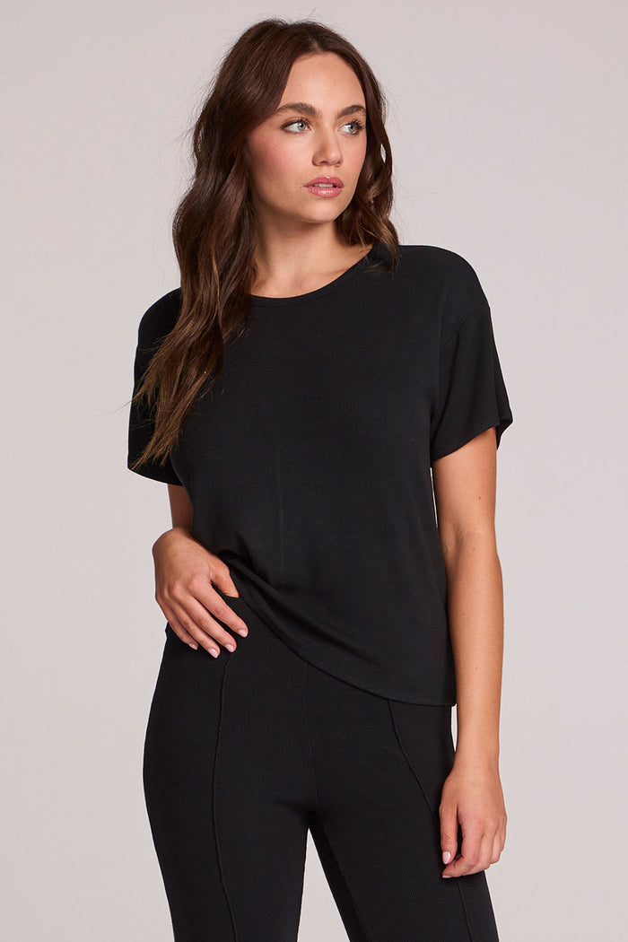 Front view of a woman wearing the Chaser   Leonor Black Tee on a neutral background
