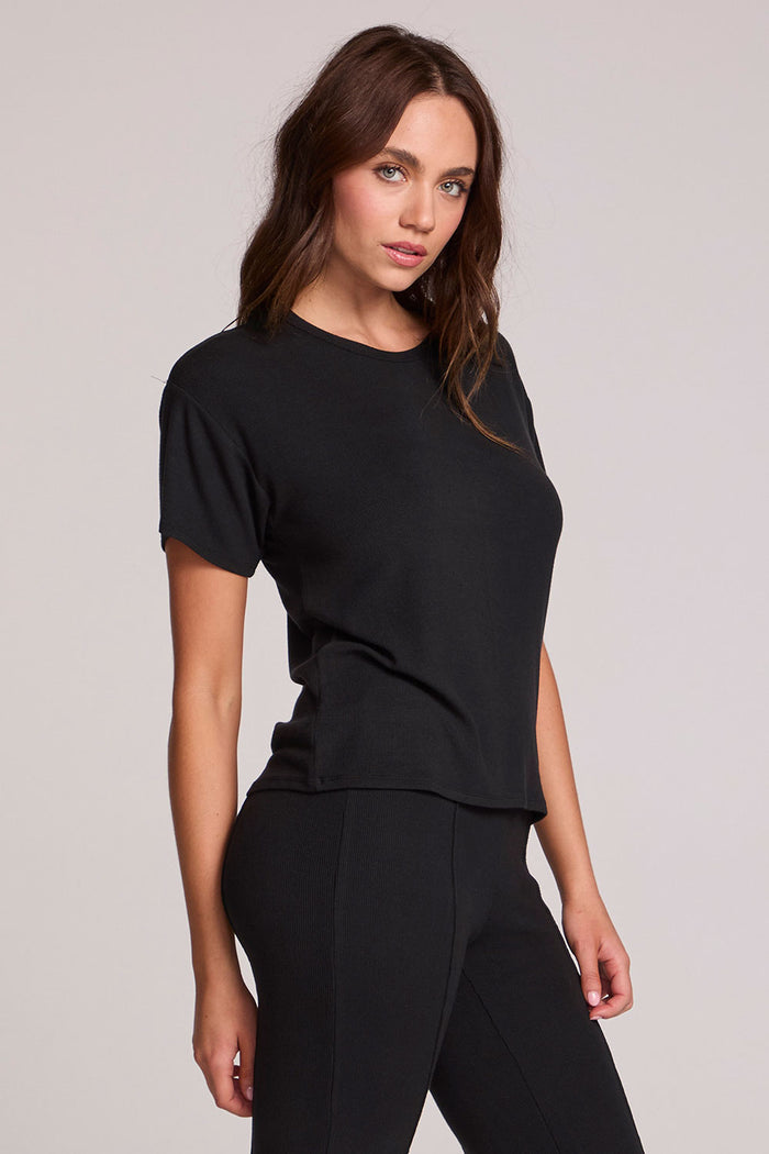 Front  angled view of a woman wearing the Chaser   Leonor Black Tee on a neutral background with black pants