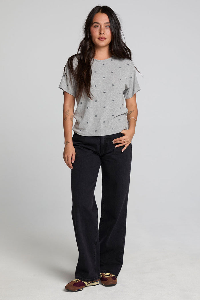 Full body view of a woman wearing the Chaser Leonor Light Heather Grey Tee on a neutral background with black pants and sneakers
