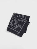 Black silk pocket square with white leopards printed on the fabric, folded diagonally on a grey background.
