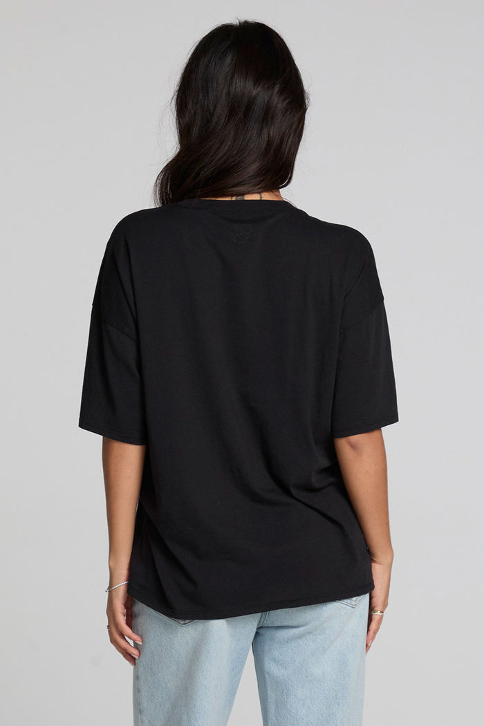 Back view of a woman wearing the Chaser Let's Get Spooky Tee on a neutral background with jeans