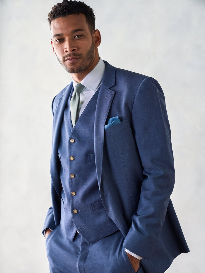 Man in light blue three-piece suit with vest, sage tie, and blue pocket square