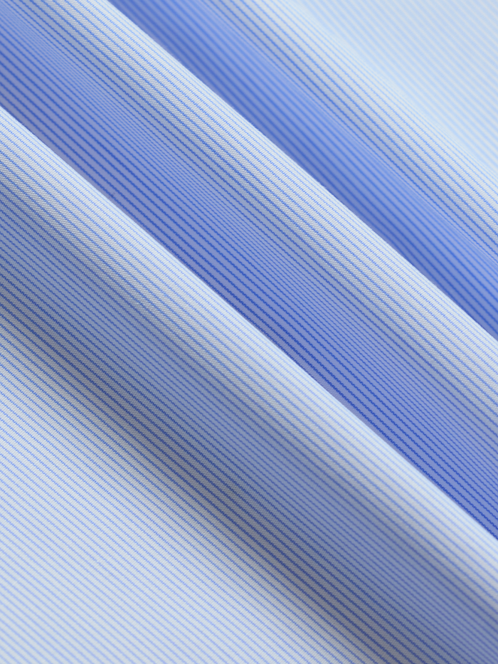 Close-up of light blue and white striped dress shirt fabric with folds