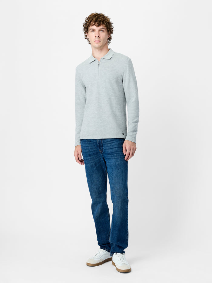 A man wearing a long sleeve grey polo shirt with ottoman texture, a regular fit, a collared neckline and a branded half zip.