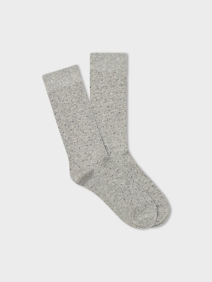 Pair of light grey dress socks with small dark pindot pattern, folded flat on light grey background