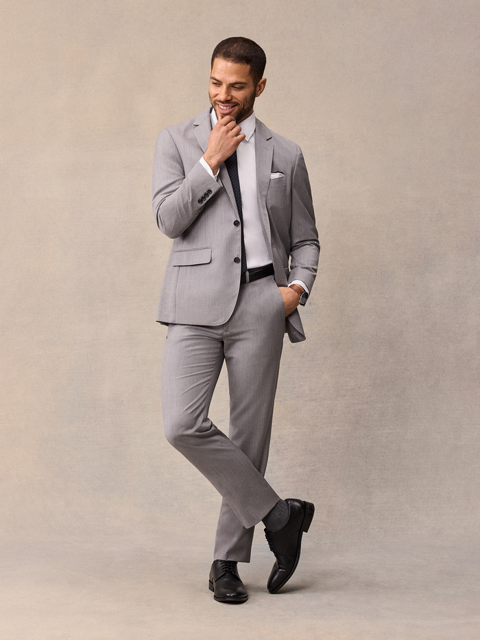 Man in light grey suit, navy pindot tie, walking pose, black shoes
