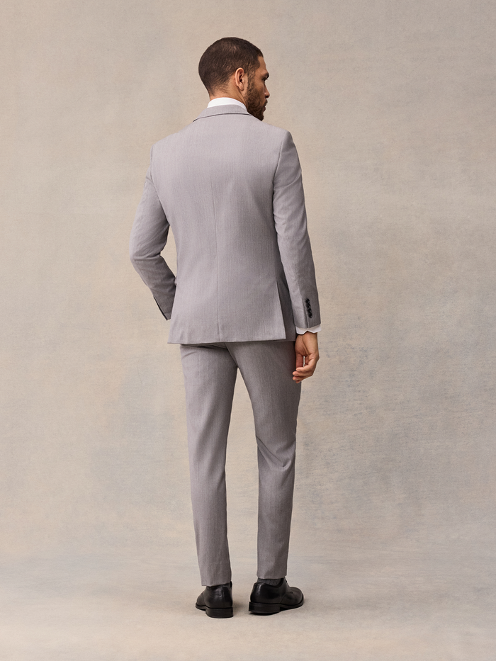 Back view of man in light grey suit, full-length, black shoes