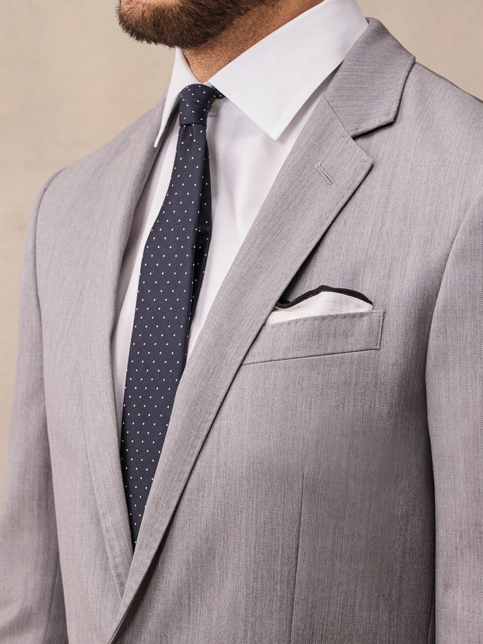 Close-up of light grey suit jacket lapel, pocket square, and tie knot