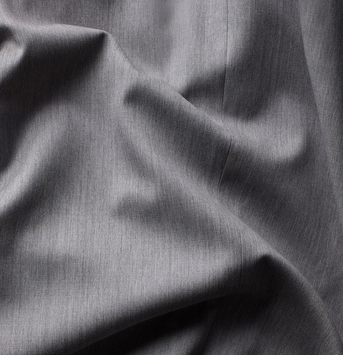 Close-up of light grey suiting fabric with folds, showing woven texture