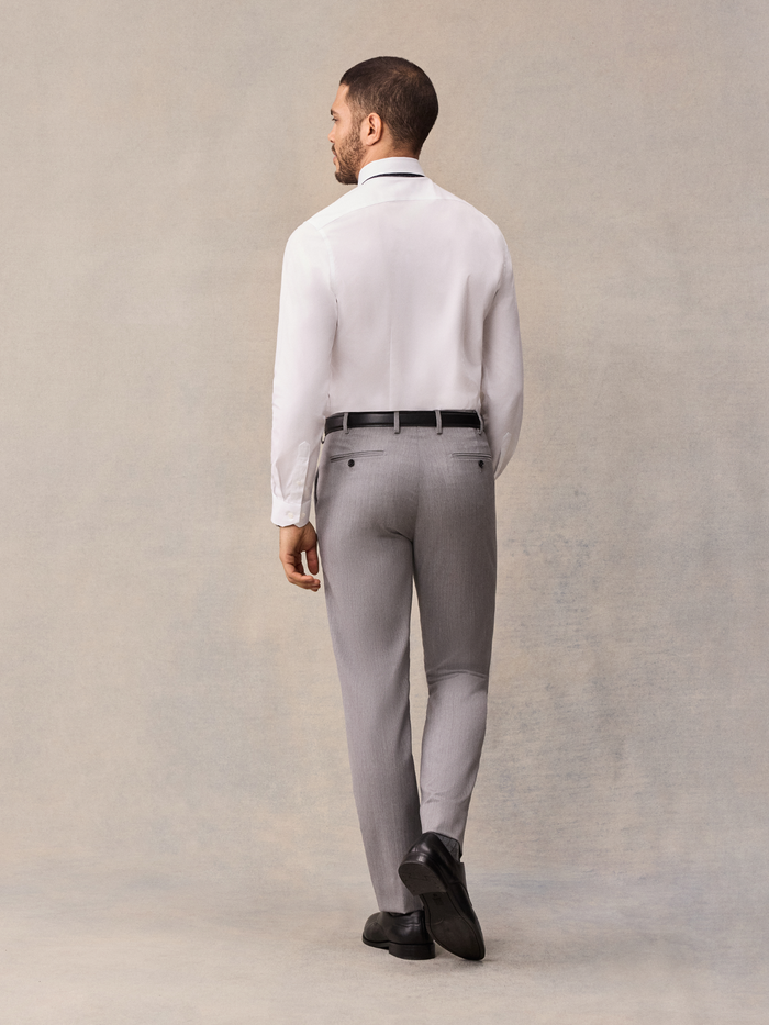 Back view of man in white dress shirt and light grey trousers with black belt