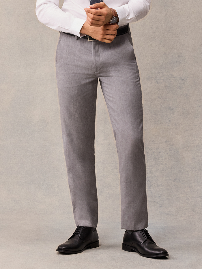 Cropped front view of light grey suit trousers with black belt and shoes