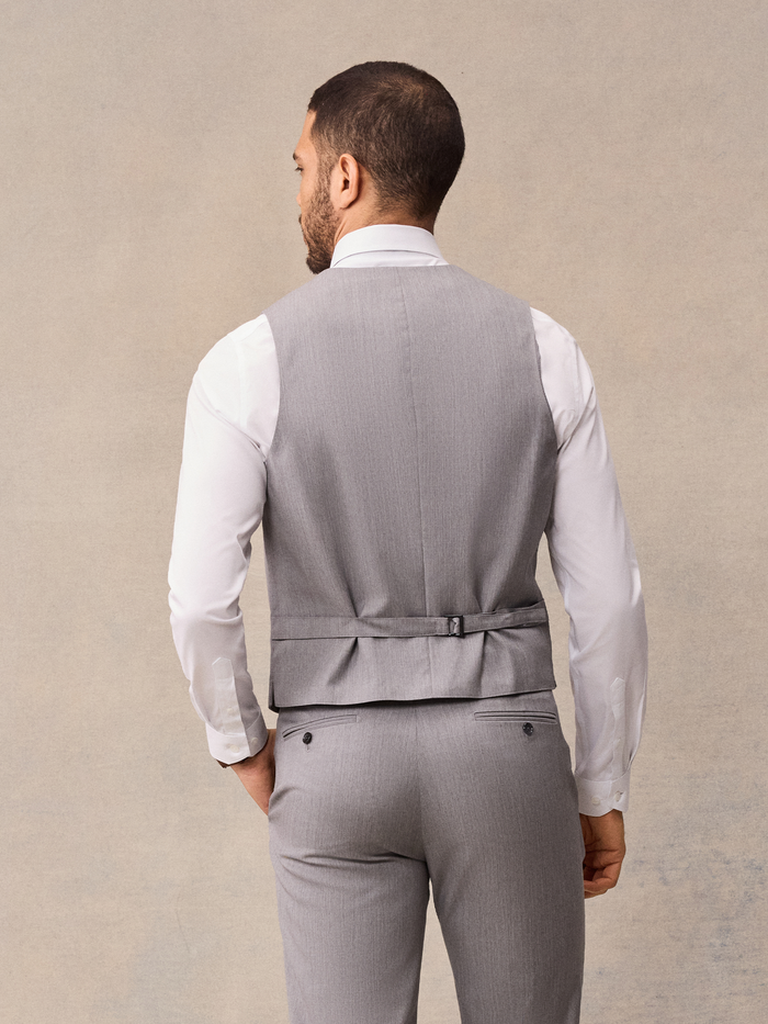 Back view of man in light grey suit vest with adjustable strap buckle